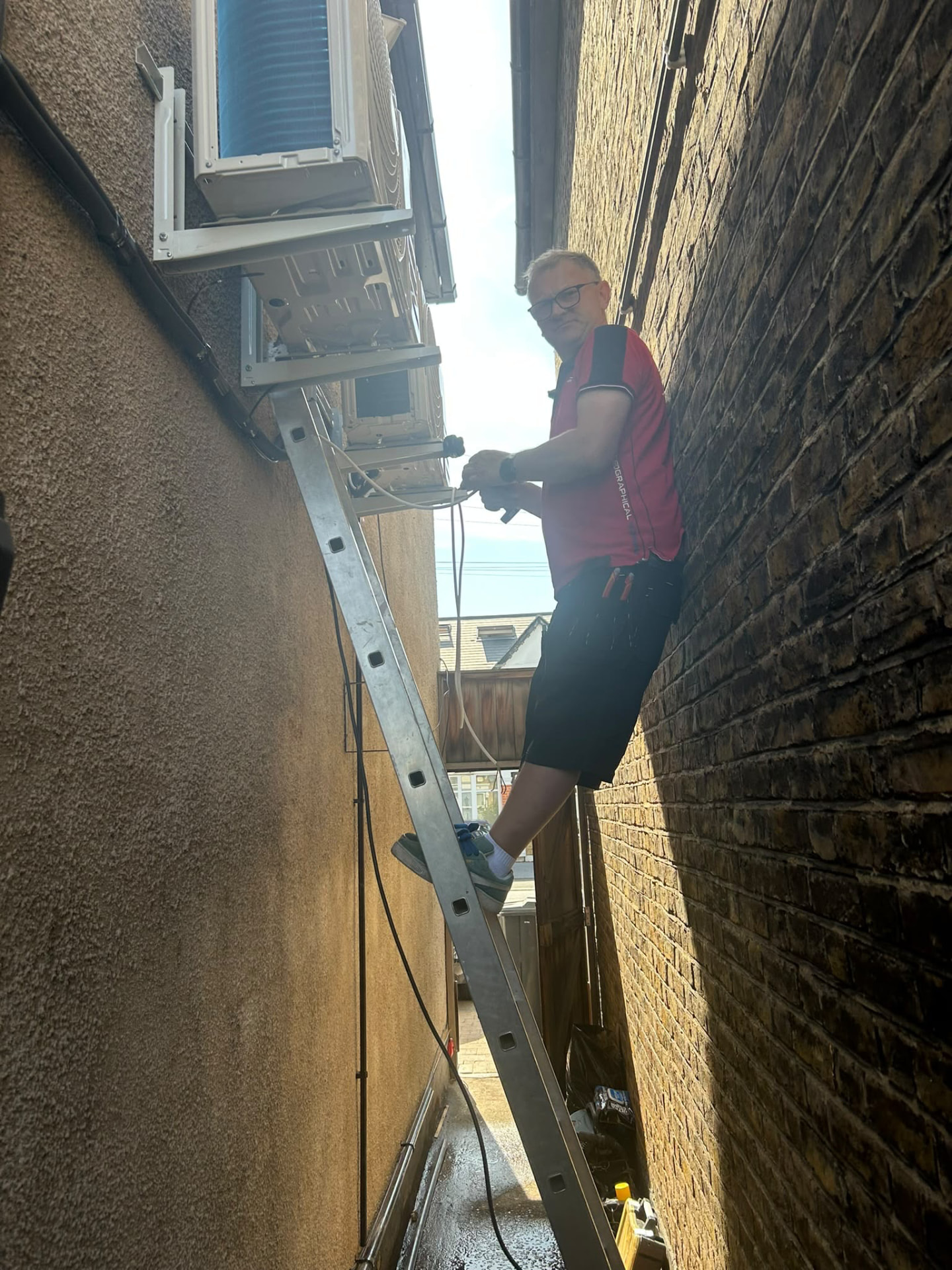 Air conditioning engineer working safely on outdoor wall-mounted units