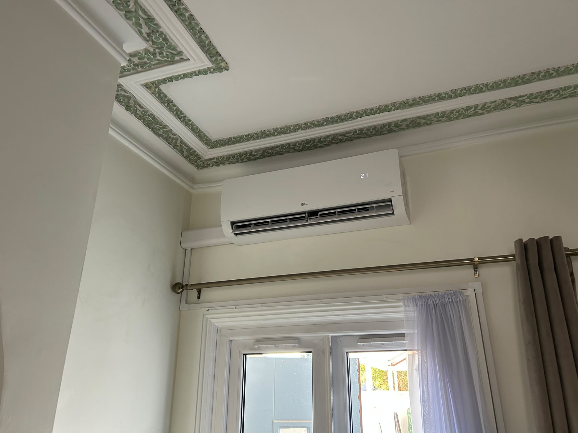 LG wall-mounted air conditioner installed above a bedroom window