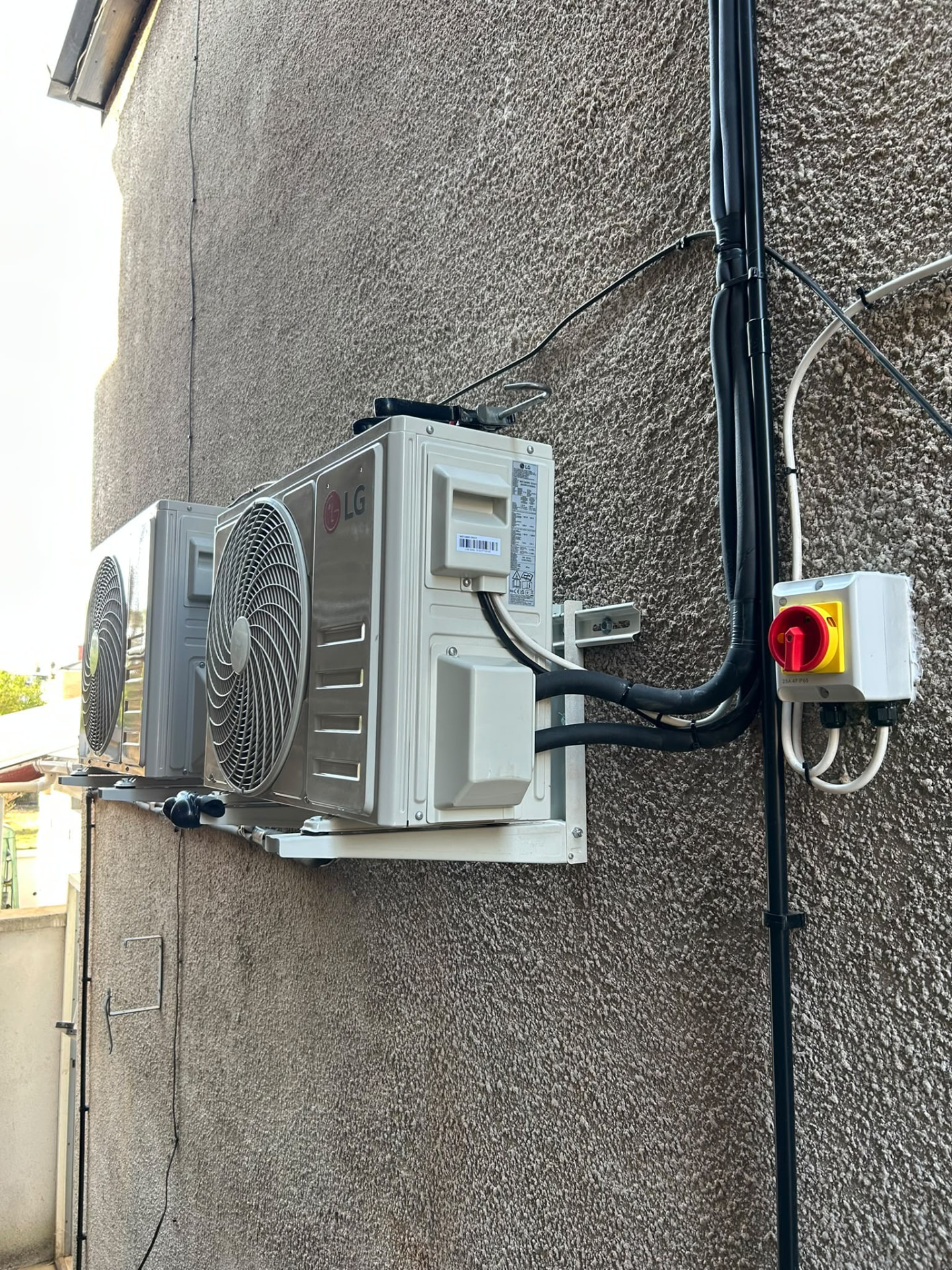 Two LG air conditioning outdoor units mounted securely to an exterior wall
